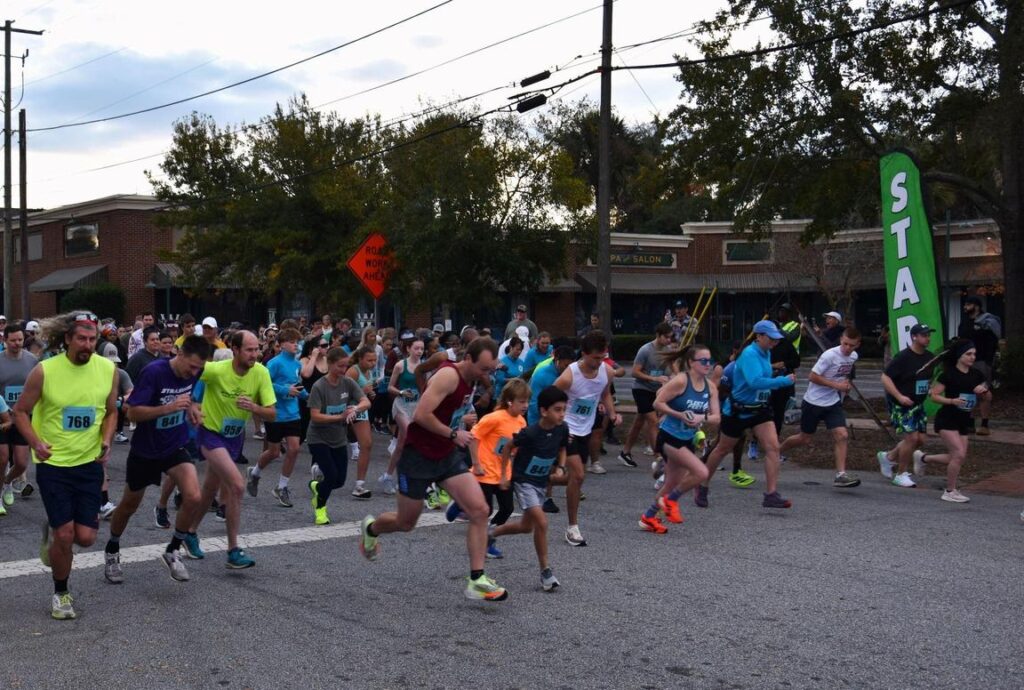 Runners start a race on a street, with a "START" banner and spectators in the background.