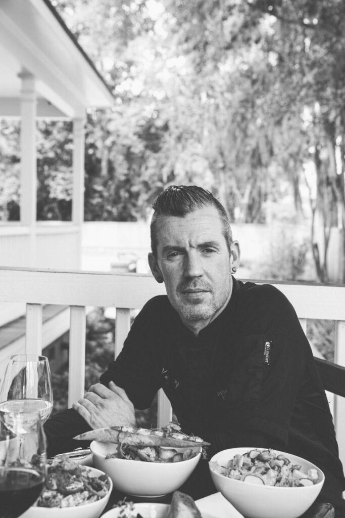 A man sits at a table with various bowls of food, looking thoughtfully at the camera.