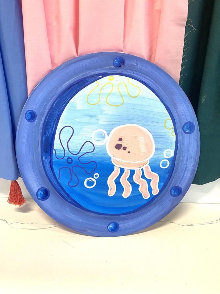 A circular blue frame displays a painted jellyfish with bubbles and colorful swirls in the background.