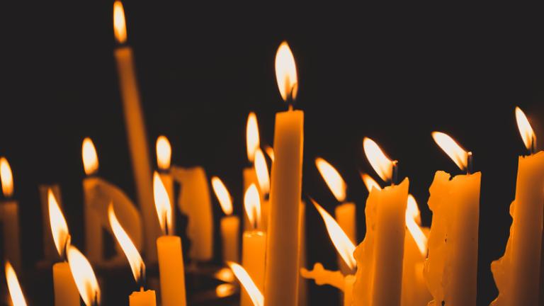 Multiple lit candles illuminate a dark background, casting a warm glow.