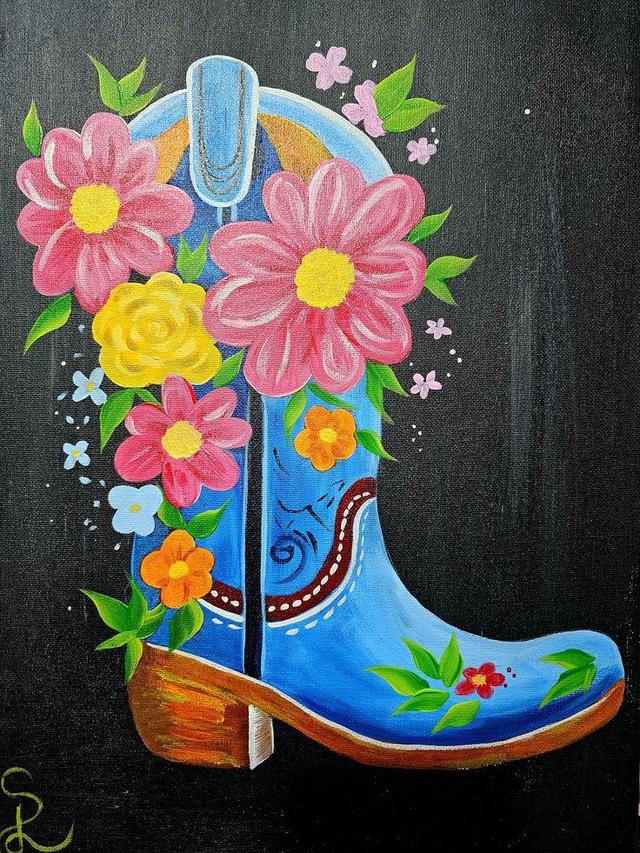 A blue cowboy boot adorned with colorful flowers and green leaves against a black background.