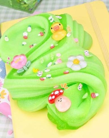 A vibrant green slime with cute decorations, including a rubber duck, flowers, and mushrooms.