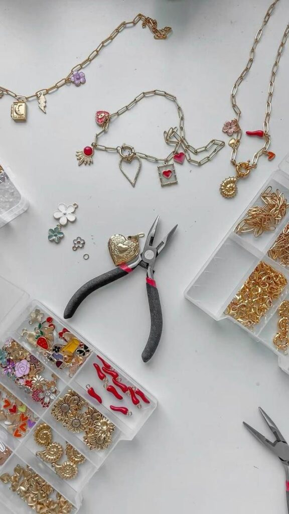 Jewelry-making tools and various charms arranged on a table, including pliers and decorative pieces.