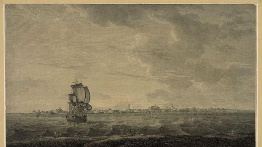 A sailing ship navigates choppy waters near a distant shoreline with buildings under a cloudy sky.