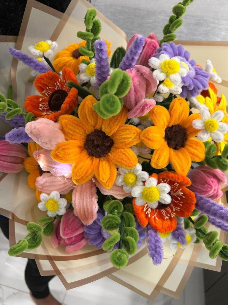 A vibrant bouquet of colorful pipe cleaner flowers, featuring sunflowers, tulips, and daisies.
