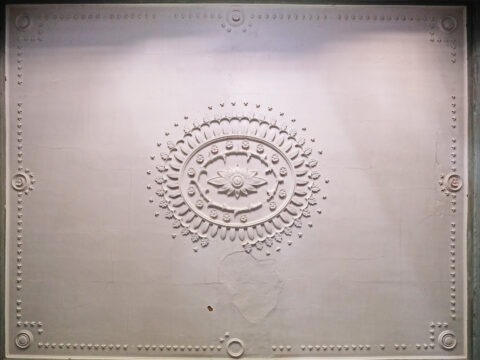 Decorative plaster ceiling with an ornate circular design and intricate border details.